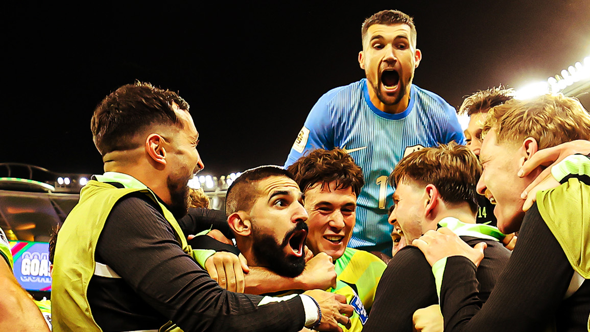 Australian men's footballers celebrating in a stadium.