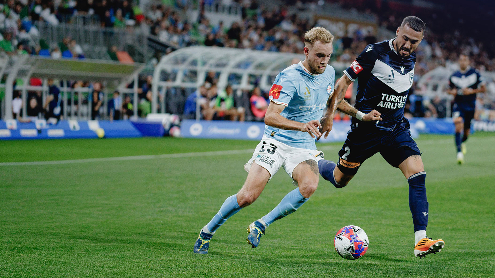 Melbourne Victory and Melbourne City FC footballers in action on field.