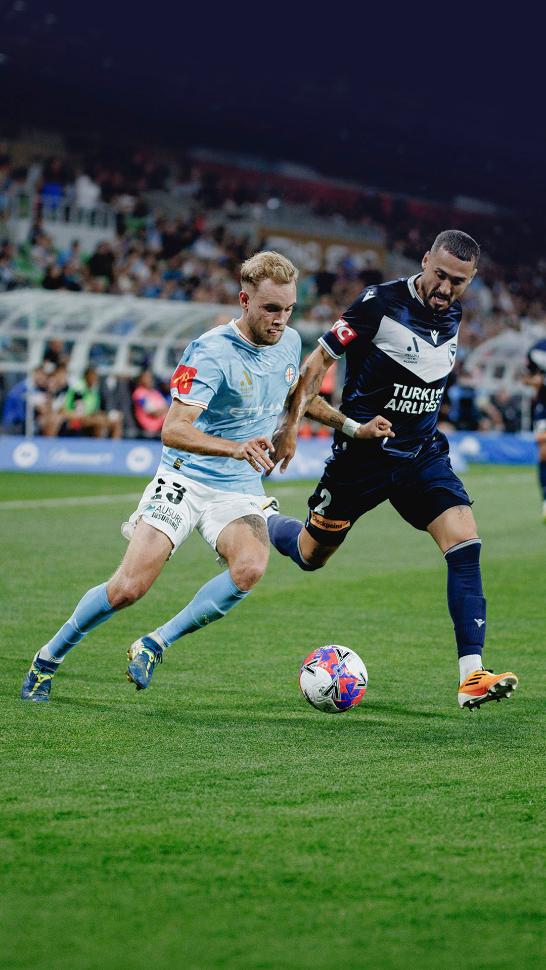 Melbourne Victory and Melbourne City FC footballers in action on field.